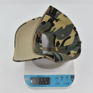Detailed top view of a camouflage kids baseball cap being weighed on a digital scale