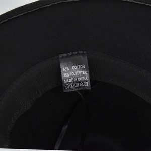 Dettaglio macro dell'etichetta interna che mostra 65% cotone e 35% poliestere del cappello