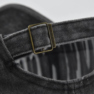 Black washed cotton baseball cap featuring an adjustable antique bronze metal buckle strap