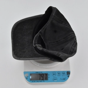 Close-up showing the weight of a black washed cotton baseball cap on a digital scale
