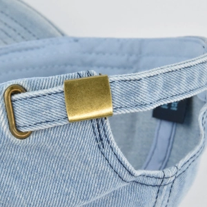 Detailed view of light blue denim baseball cap with adjustable retro brass metal buckle