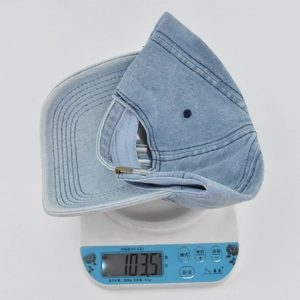 Close-up of light blue denim baseball cap on a digital scale showing weight of 103.5g