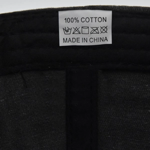 Detail showing the 100% cotton material tag and inner stitching of the black baseball cap