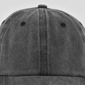 Close-up of washed cotton baseball cap crown with stitched eyelets and metal button detail