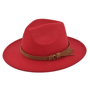 Detail of red fedora hat featuring a brown leather belt with metal ring and tassel decor