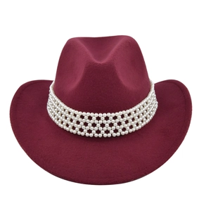 Détail d'un chapeau de cowboy en laine rouge foncé avec un bandeau décoratif en perles