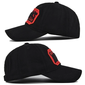 Close-up detail of the 3D embroidered red and black MTS label on a black cotton baseball cap
