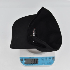 Detail showing the lightweight 93.3g black baseball cap on a scale for product weight info