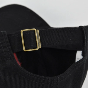 Detail of adjustable cotton baseball cap with vintage gold metal buckle on black strap