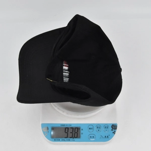 Close-up showing the weight of the black 3D embroidered baseball cap on a scale