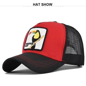 Close-up of the toucan embroidery patch on the red and black mesh trucker cap