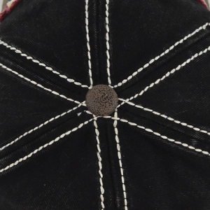 Détail macro de la couronne de casquette avec coutures blanches contrastées et bouton mat