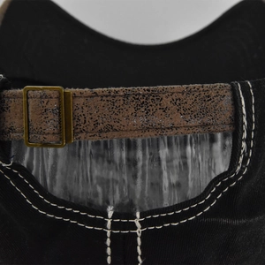 Détail de la sangle réglable marron et de la boucle en bronze sur la casquette de baseball