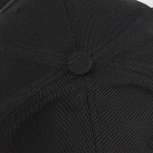 Detailed macro view of black cotton twill baseball cap crown with button and stitching