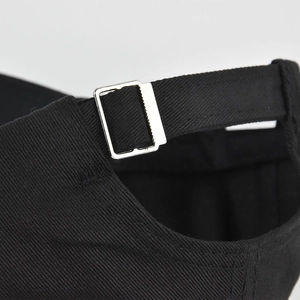 Detail of adjustable metal buckle and black twill fabric strap on the back of baseball cap