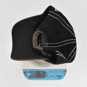 Vue détaillée d'une casquette de baseball noire avec coutures blanches pesée sur balance