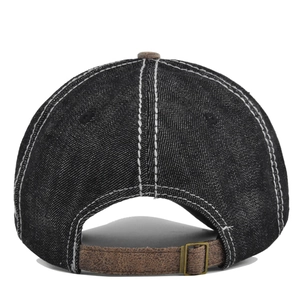 Detail view of washed black denim baseball cap with white stitching and leather back strap