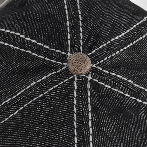 Close-up of baseball cap crown with white contrast stitching and a patterned top button