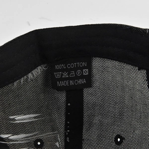 Detail of internal cotton label and stitching on a black washed denim baseball cap