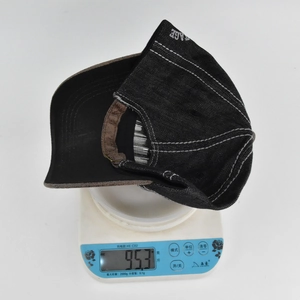 Detail showing the 95.3g weight of the vintage black denim baseball cap on a scale
