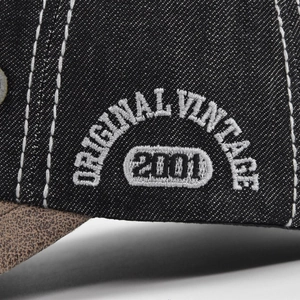 Macro detail of the 3D 'ORIGINAL VINTAGE 2001' white embroidery on black denim cap