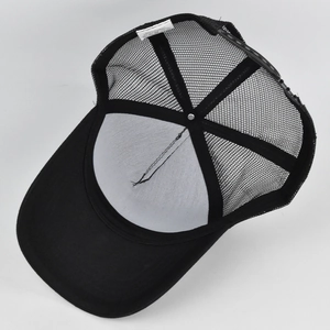 Detail of black trucker hat showing breathable mesh back and cotton material label