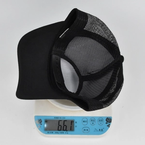 Detailed view of lightweight black mesh baseball cap weighing 66.1 grams on a scale