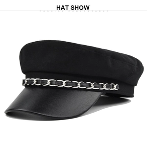 Dettaglio del berretto newsboy nero con corona in lana, visiera in pelle e catena