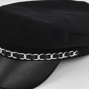 Dettaglio del berretto nero con catena in metallo argento e visiera in pelle a grana fine