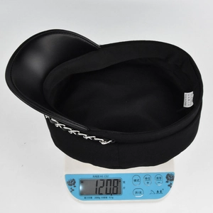 Dettaglio del cappello nero in ecopelle PU sulla bilancia con un peso leggero di 120,8 g