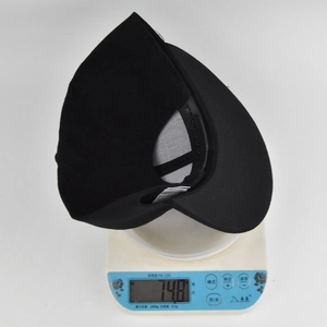 Detailed shot of a black snapback baseball cap on an electronic scale weighing 74.8 grams