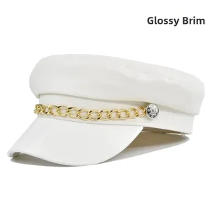 Detail of white baker boy hat featuring a glossy brim and decorative gold chain accent