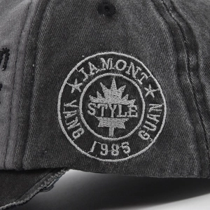Close-up of vintage skull embroidery and maple leaf patch on washed canvas baseball cap
