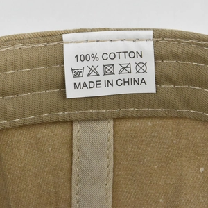 Dettaglio dell'etichetta di lavaggio del cappellino in cotone con indicazione 100% cotone