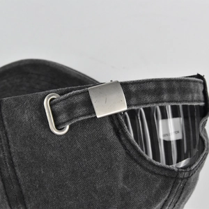 Detail of adjustable metal buckle and 100% cotton label on washed denim baseball cap