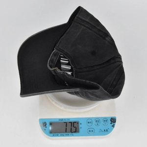 Close-up of a vintage washed grey cotton baseball cap showing 77.5g weight on a scale