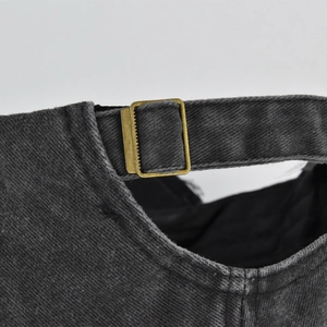 Detail of adjustable brass buckle and washed denim texture on vintage baseball cap