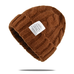 Detailed texture of brown cable knit wool hat featuring a white fashion fabric label