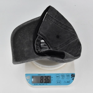 Detailed view of dark grey distressed baseball cap on scale weighing 83.6g