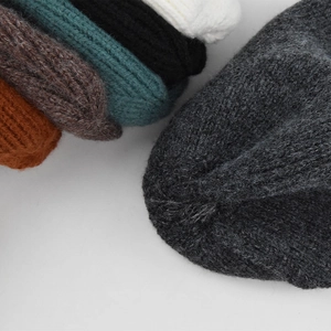Dettaglio di berretti in maglia spessa in vari colori con trama a maglia intrecciata