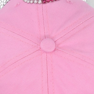 Detailed macro view of pink cotton twill baseball cap top with sparkling rhinestones