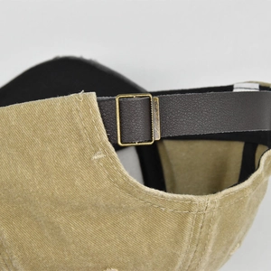 Detail of vintage corduroy baseball cap with adjustable leather strap and bronze metal buckle