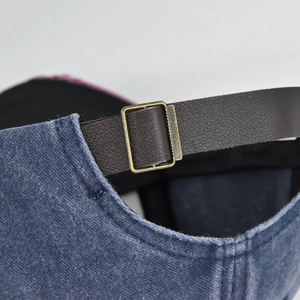 Detail des verstellbaren Lederriemens und der Bronzeschnalle an der gewaschenen Denim-Kappe