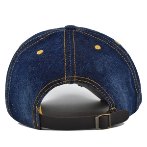 Macro detail of the denim baseball cap showing leather strap and vintage metal buckle