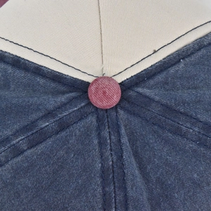 Detail of multi-color baseball cap top with corduroy button and distressed denim texture