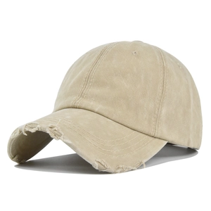 Dettaglio del cappellino da baseball kaki lavato con bordi sfilacciati e fori consumati