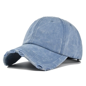 Dettaglio dei bordi sfrangiati e della texture in denim invecchiato sul cappellino blu