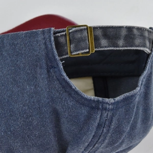 Detail of adjustable brass metal buckle and vintage washed denim strap on baseball cap