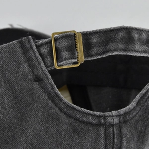 Detailed close-up of distressed denim baseball cap featuring vintage bronze metal buckle