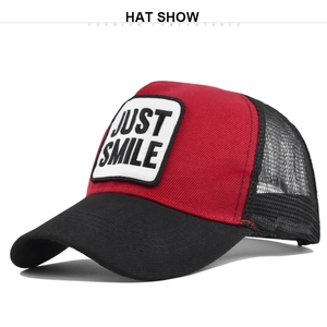 Detail of red and black trucker hat featuring JUST SMILE embroidery and mesh back